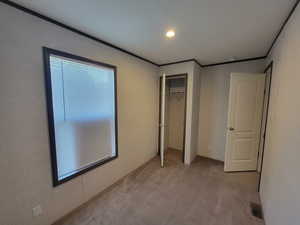 Unfurnished bedroom with light colored carpet, recessed lighting, a closet, and ornamental molding