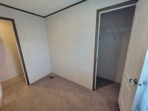 Unfurnished bedroom with carpet, ornamental molding, and a closet