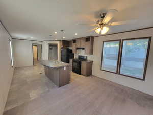 Kitchen with black appliances, plenty of natural light, a sink, a center island with sink, and recessed lighting