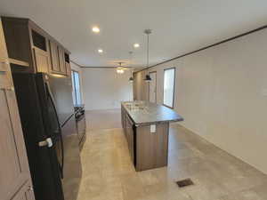 Kitchen featuring black appliances, dark countertops, recessed lighting, a center island with sink, and a sink