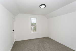 Additional living space with lofted ceiling, carpet flooring, and baseboards