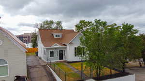View of front of property with a fenced front yard, a gate, and roof with shingles