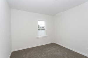 Spare room with dark colored carpet and baseboards