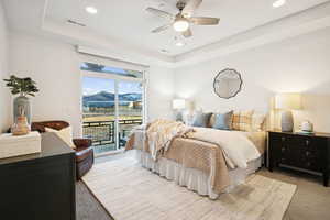 Carpeted bedroom featuring access to outside, a raised ceiling, ceiling fan, recessed lighting, and a mountain view
