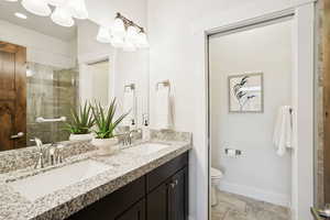 Full bathroom featuring double vanity and tiled shower