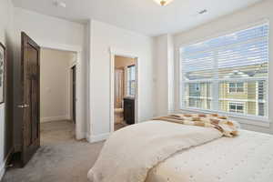 Bedroom featuring light colored carpet and ensuite bath