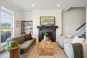 Living room with a fireplace, stairs, crown molding, and recessed lighting