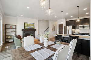 Dining room with recessed lighting, light wood-style flooring, and a lit fireplace