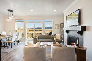 Living room featuring ornamental molding, a warm lit fireplace, wood finished floors, and recessed lighting