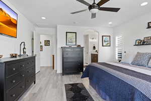 Bedroom with light wood finished floors, arched walkways, recessed lighting, a ceiling fan, and ensuite bathroom