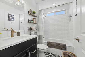 Bathroom with tiled shower / bath, vanity, and toilet