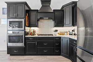 Kitchen featuring stainless steel appliances, tasteful backsplash, and dark cabinetry