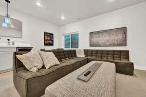 Living room with recessed lighting, bar area, light carpet, and baseboards