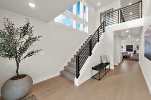 Staircase featuring wood finished floors, baseboards, a towering ceiling, and recessed lighting