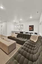 Carpeted living area featuring recessed lighting, baseboards, and bar