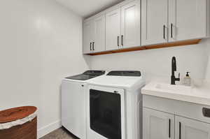 Laundry room featuring separate washer and dryer, cabinet space, and baseboards