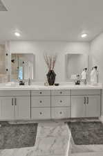 Full bathroom featuring a tile shower, double vanity, marble look tiles, and recessed lighting