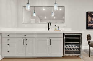Bar area with beverage cooler, decorative light fixtures, and a sink