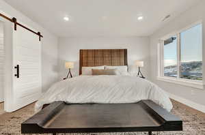 Bedroom featuring a barn door, recessed lighting, and baseboards