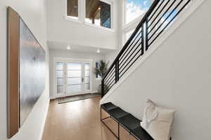 Entryway featuring stairs, healthy amount of natural light, a towering ceiling, hardwood / wood-style floors, and recessed lighting