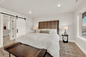 Bedroom with a barn door, baseboards, and recessed lighting