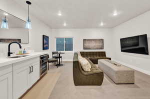 Living room featuring beverage cooler, light carpet, baseboards, and recessed lighting