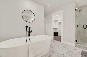 Bathroom with a spacious closet, a shower stall, marble finish floors, a soaking tub, and baseboards