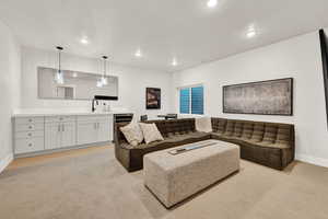 Living area featuring recessed lighting, light carpet, baseboards, and bar with sink