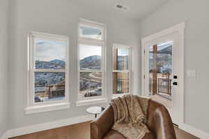 Sitting room with plenty of natural light, wood finished floors, a mountain view, and baseboards