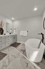 Bathroom with vanity, marble finish floors, a freestanding bath, recessed lighting, and baseboards
