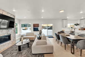 Living room featuring recessed lighting, a stone fireplace, light wood-style floors, and baseboards