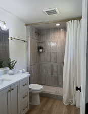 Bathroom with vanity, a tile shower, and wood finished floors