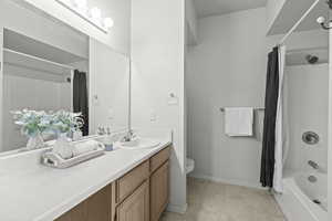 Full bathroom featuring vanity, shower / tub combo, toilet, and baseboards