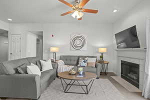 Carpeted living area with ceiling fan, a tile fireplace, recessed lighting, and baseboards