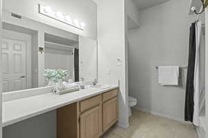 Bathroom with vanity, toilet, a shower with curtain, baseboards, and tile patterned floors