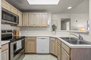 Kitchen with appliances with stainless steel finishes, light brown cabinets, a sink, light countertops, and recessed lighting