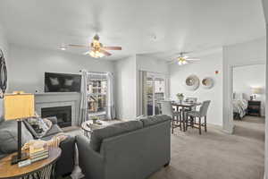 Carpeted living area with ceiling fan, a fireplace, and baseboards