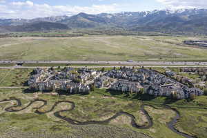 Aerial view of property and surrounding area featuring nearby suburban area and a mountainous background