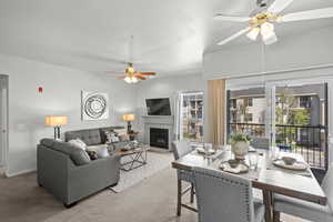 Living room with a ceiling fan, a tile fireplace, carpet, and healthy amount of natural light