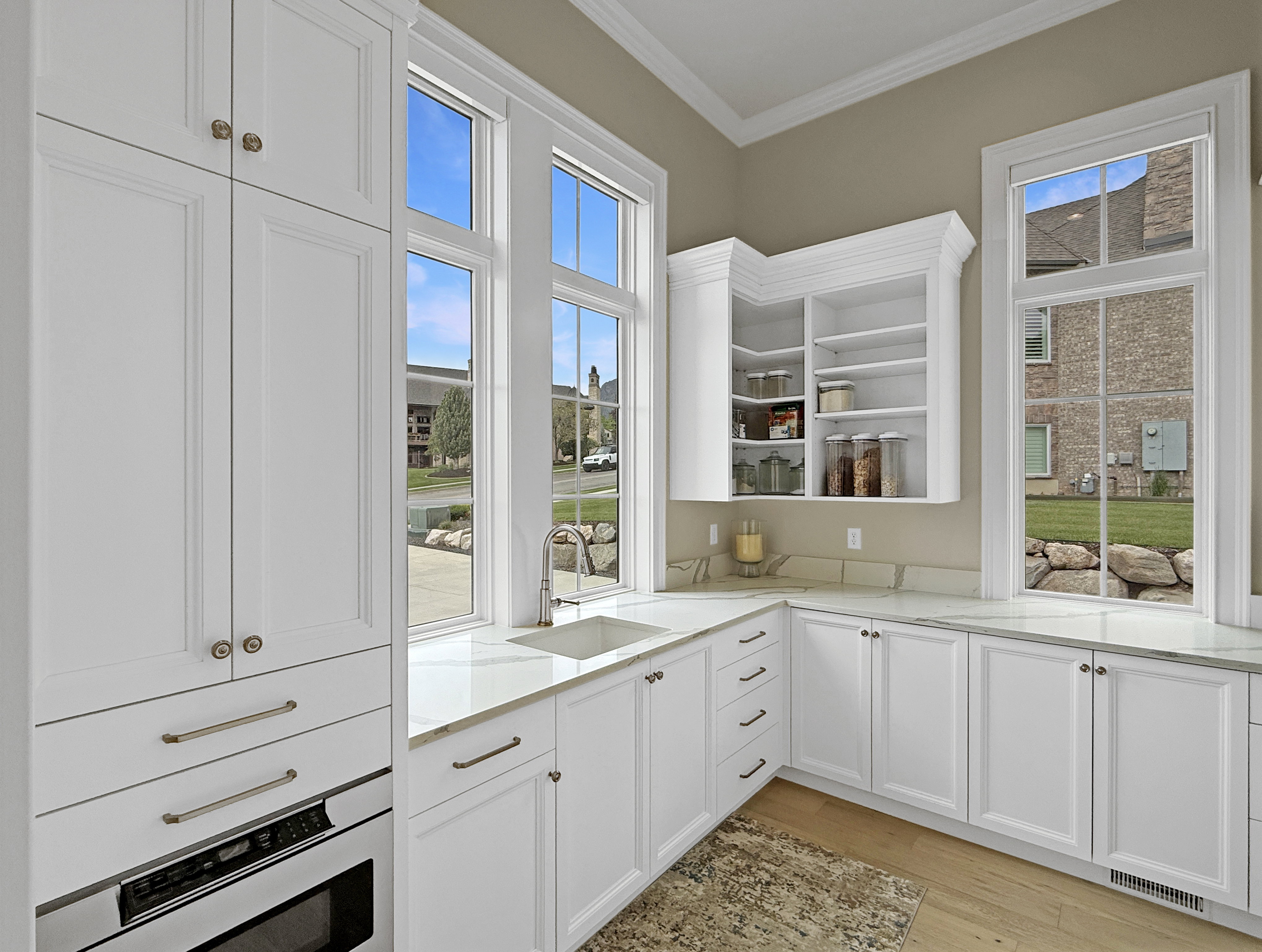 Kitchen with a sink, oven, crown molding, open shelves, and light wood finished floors