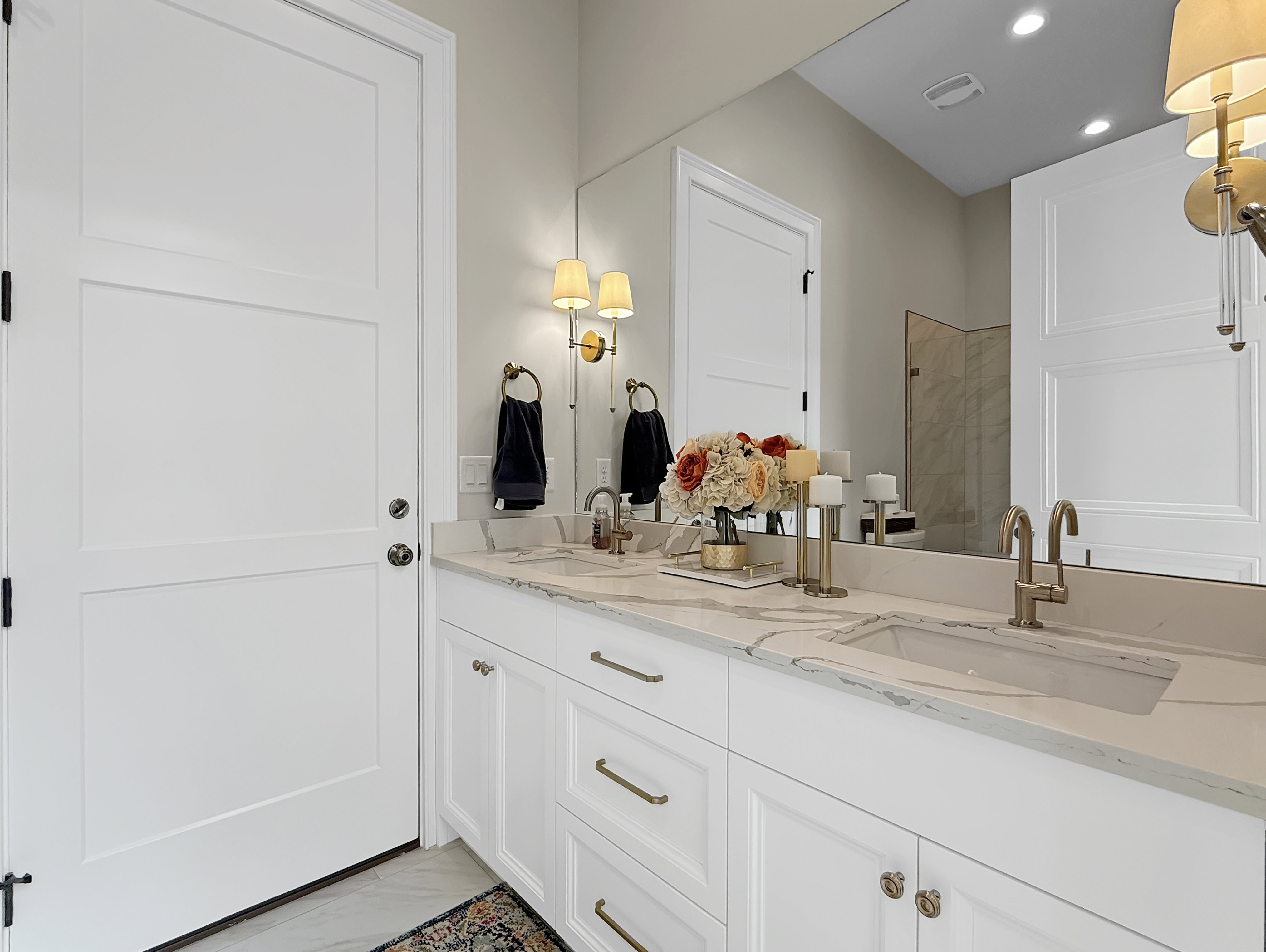 Bathroom featuring marble finish flooring, double vanity, recessed lighting, and a tile shower