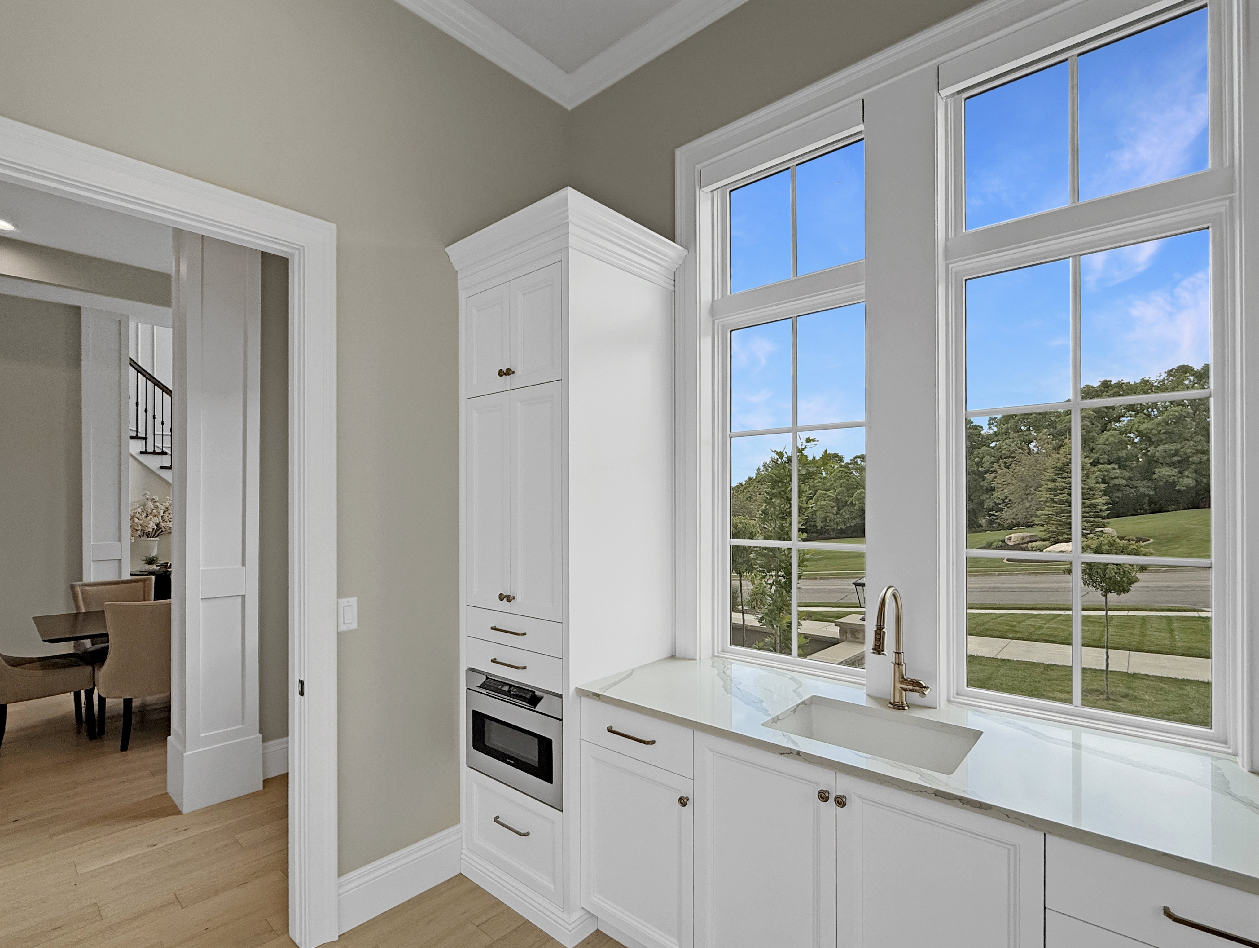 Kitchen with a sink, oven, ornamental molding, light wood-style floors, and healthy amount of natural light