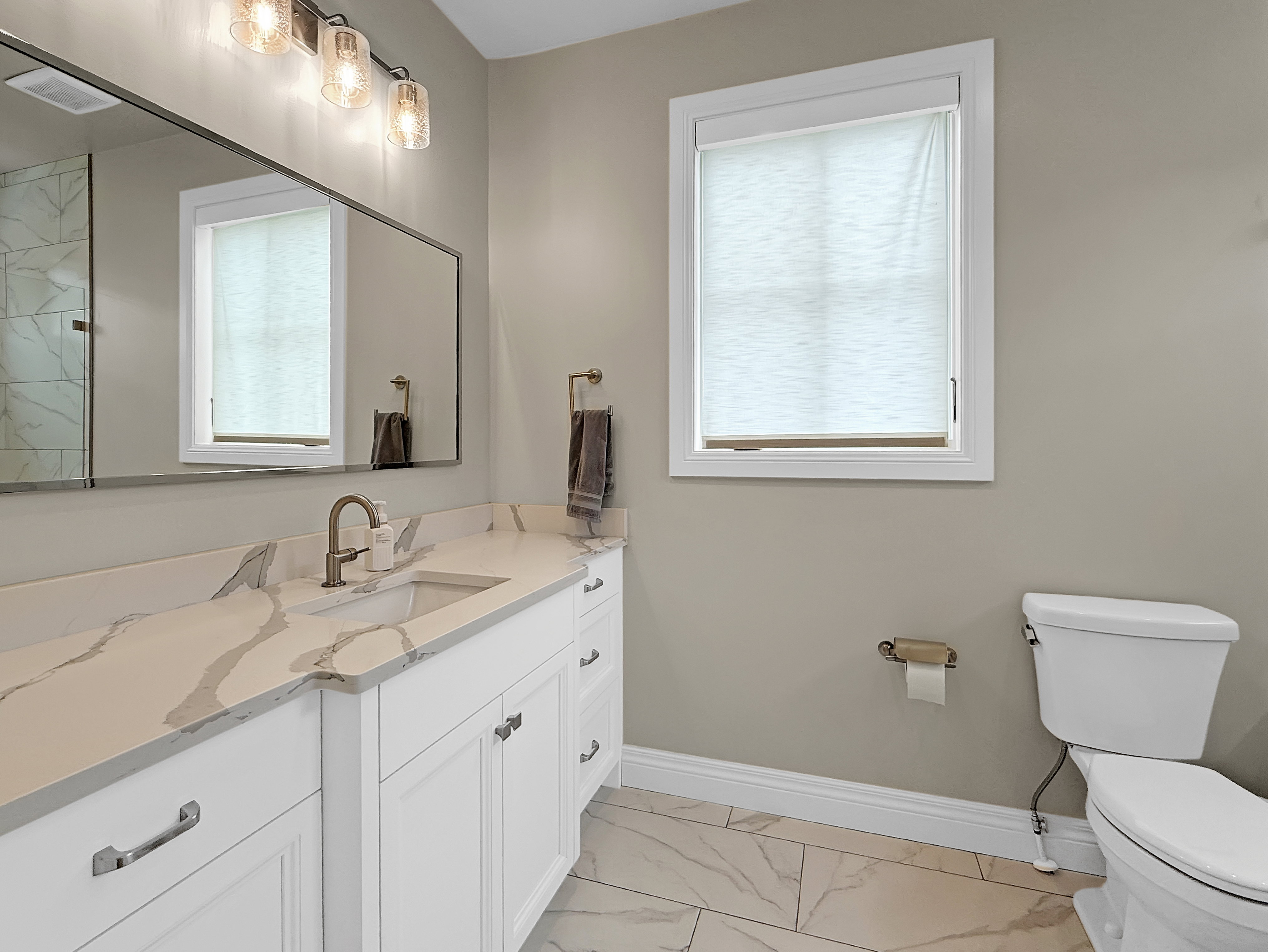 Full bathroom with marble finish floors, toilet, vanity, and baseboards