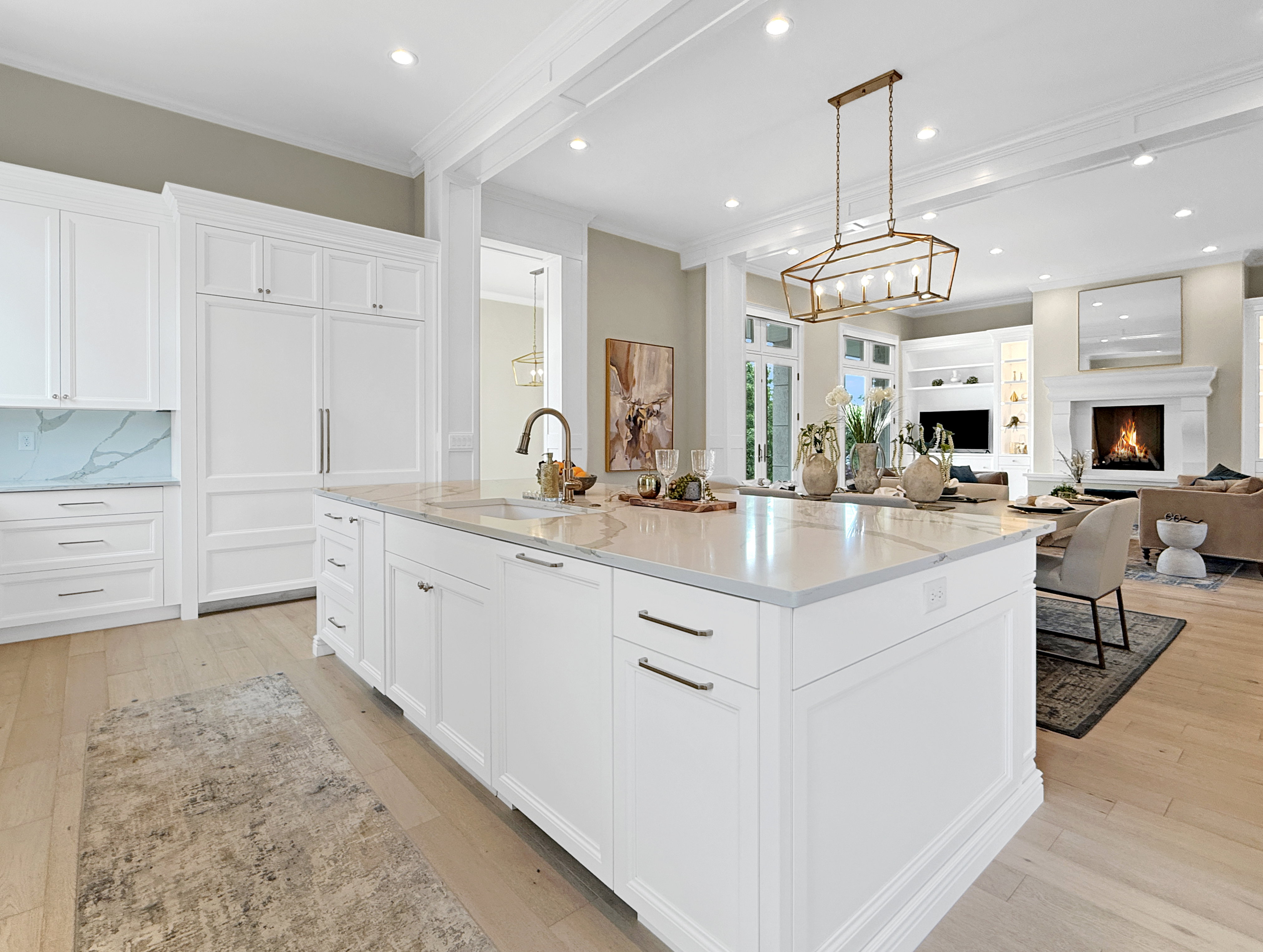 Kitchen with a sink, ornamental molding, a center island with sink, white cabinets, and light wood-type flooring