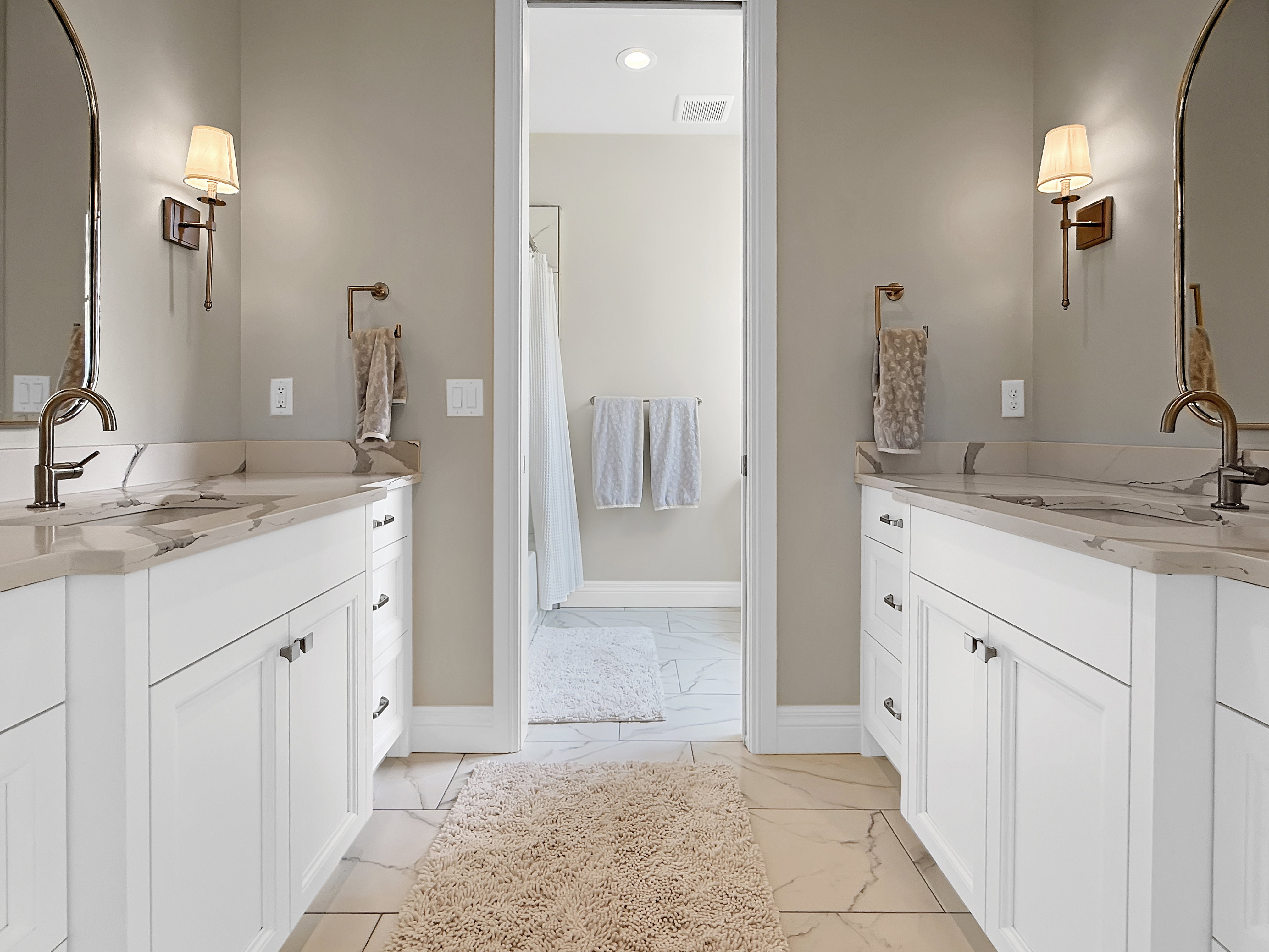 Bathroom with marble look tiles, baseboards, two vanities, recessed lighting, and a shower with shower curtain