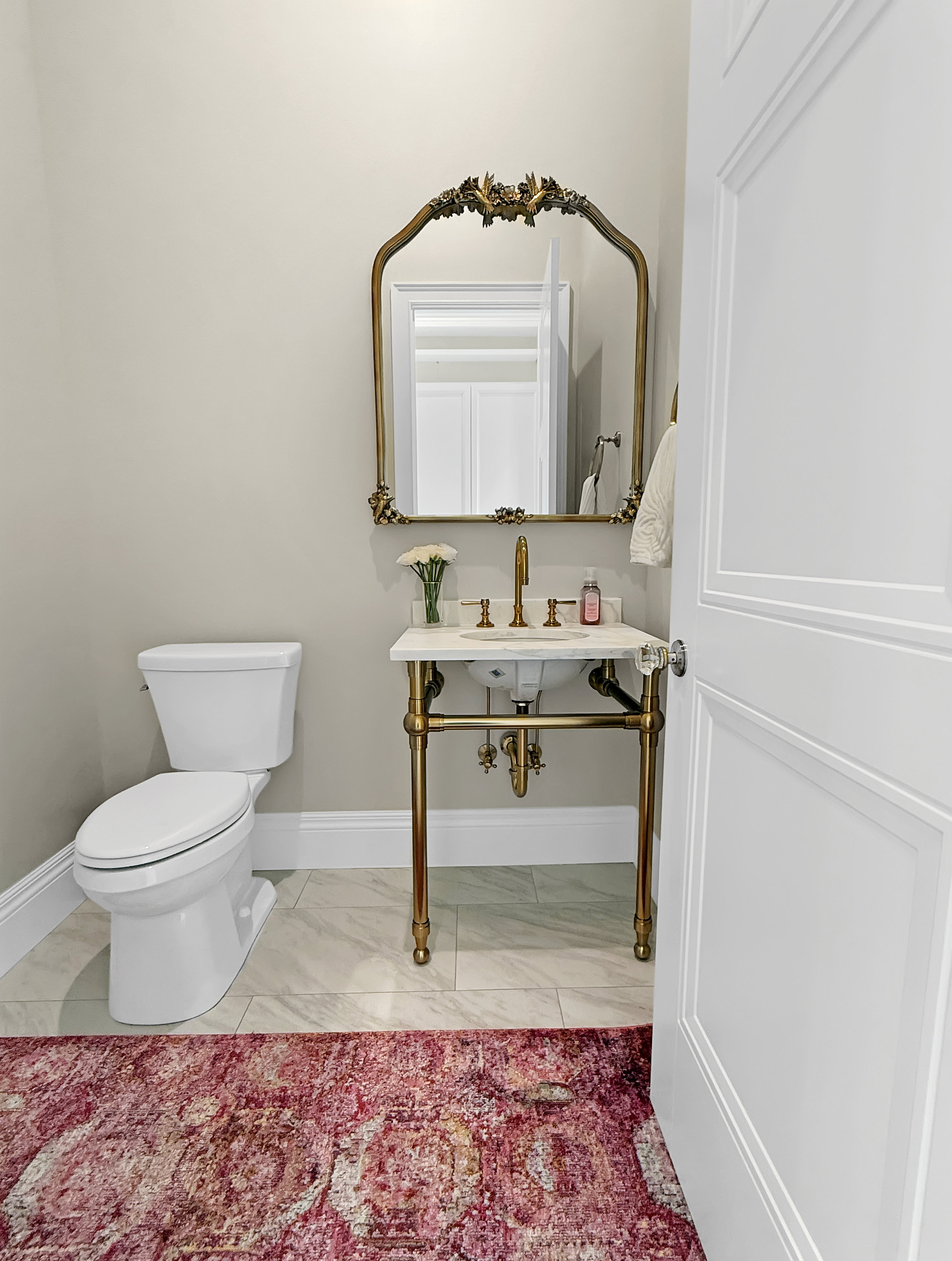 Half bath with marble look tiles, toilet, and baseboards