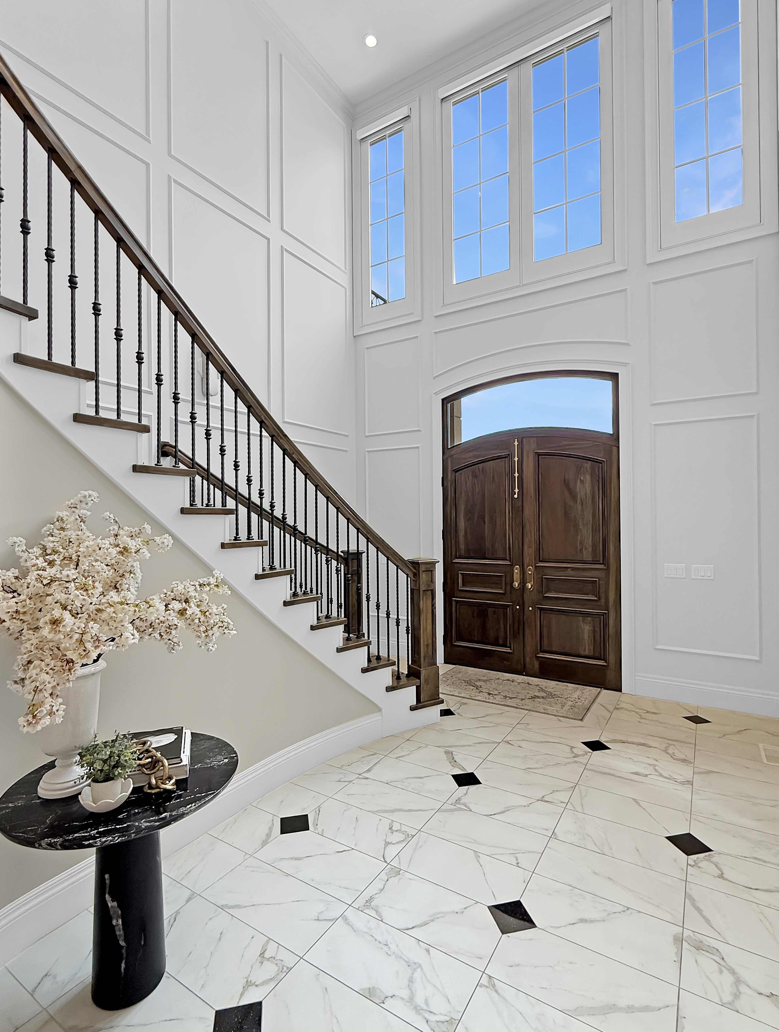Entryway with marble finish flooring, a towering ceiling, stairs, a decorative wall, and baseboards