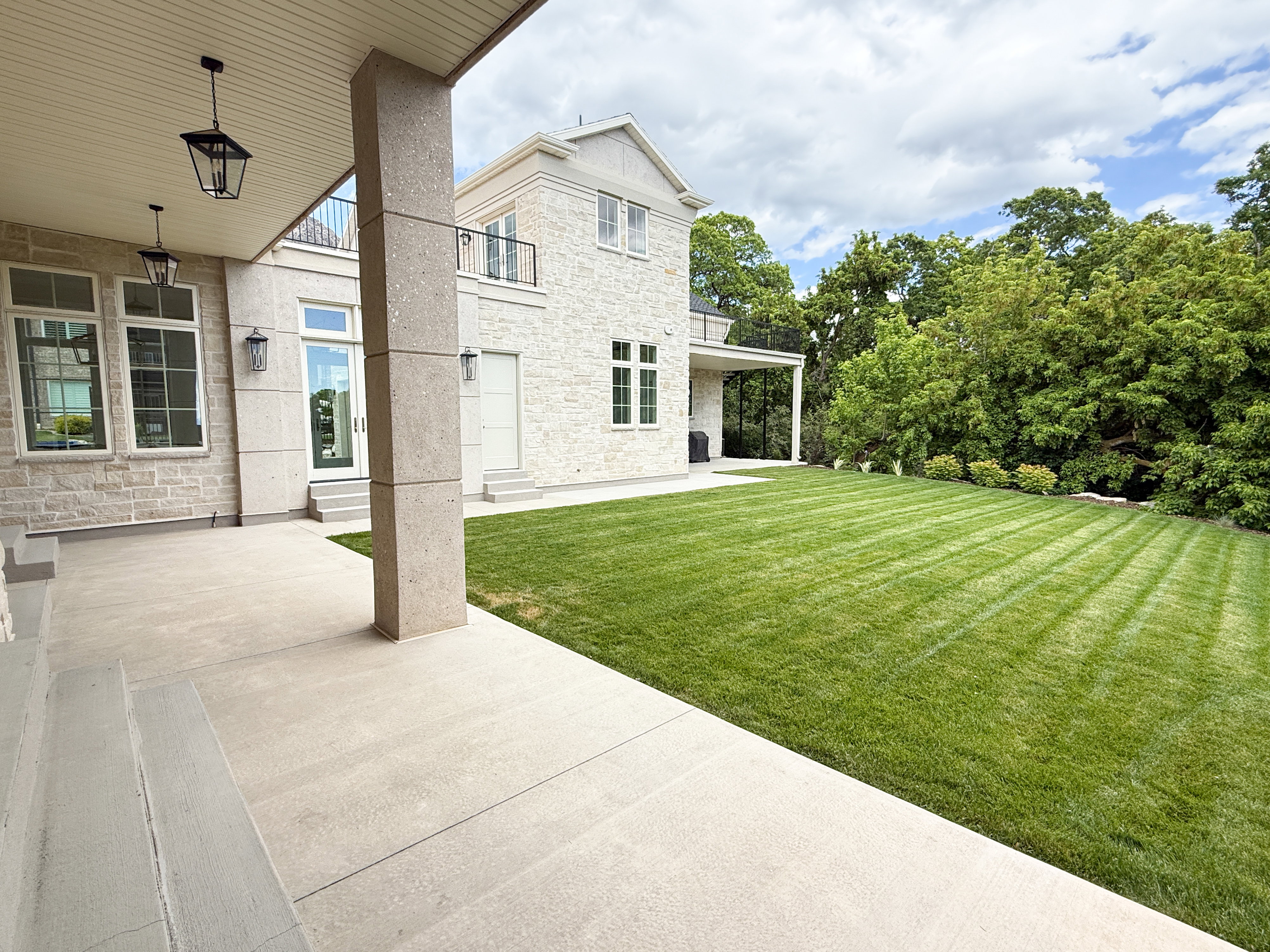 View of green lawn with a balcony and a patio