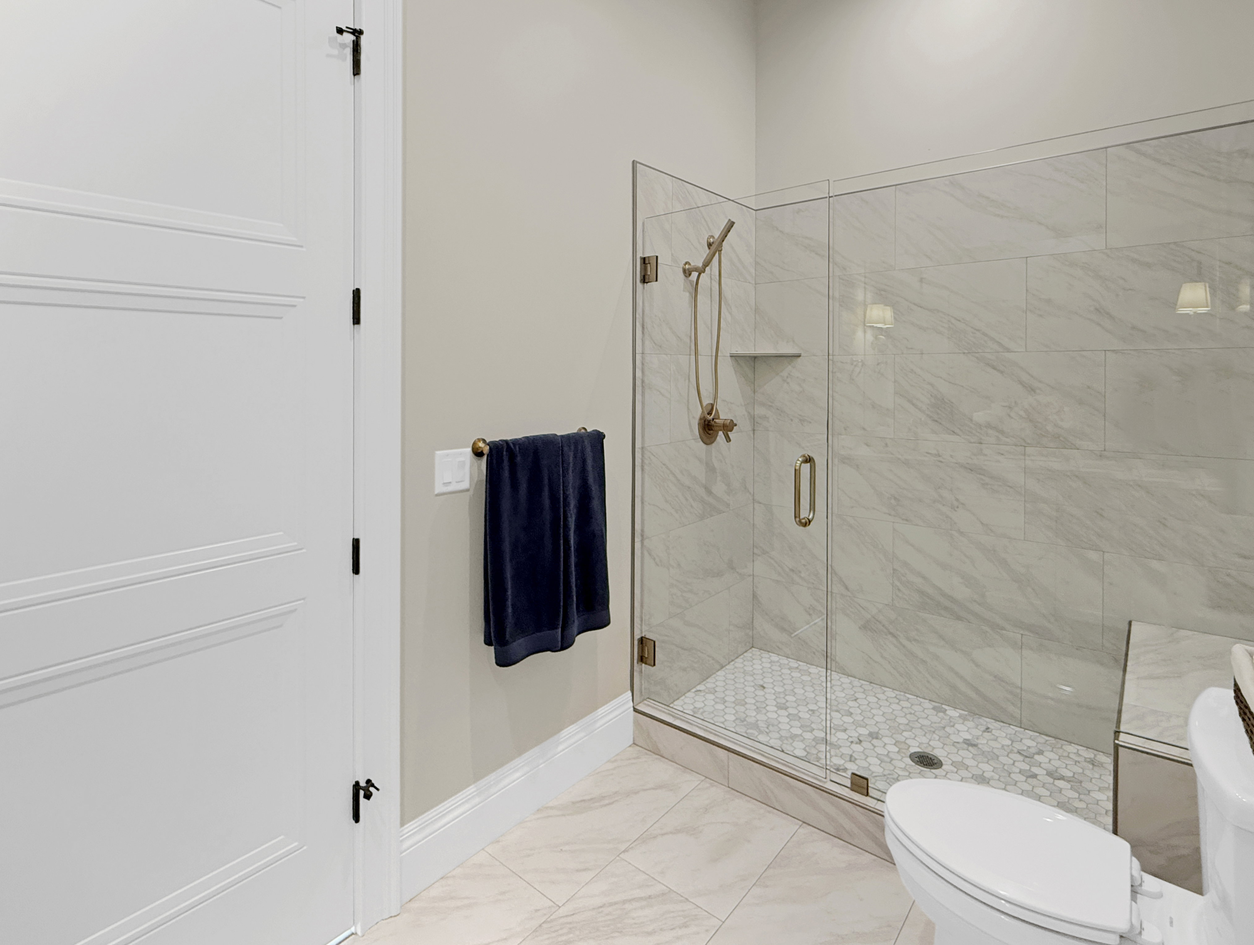 Bathroom with baseboards, a shower stall, toilet, and marble finish flooring