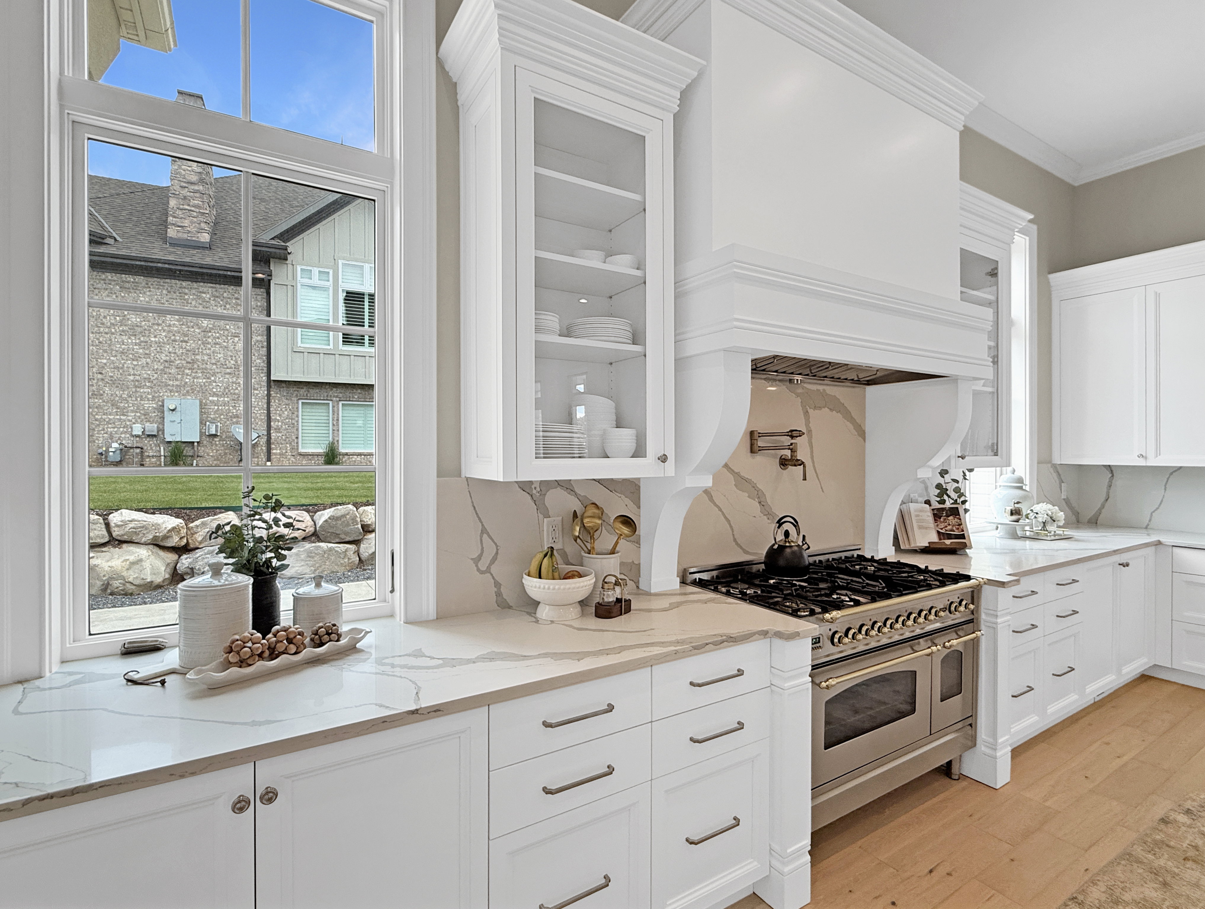 Kitchen with oven range, white cabinets, light wood-style floors, glass insert cabinets, and ornamental molding